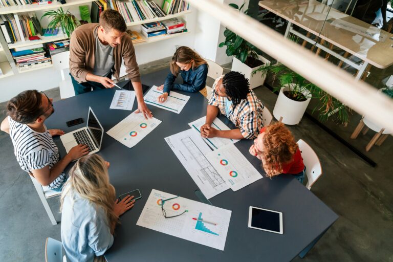 Leadership team reviewing performance data around a conference table, illustrating the tension between scale mindset and startup identity in growth-stage companies navigating organizational scaling.